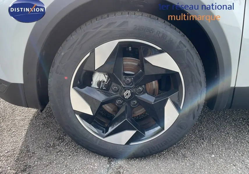 Gros plan sur la roue avant droite du Renault Captur blanc nacré avec jante noire et argentée au design moderne.