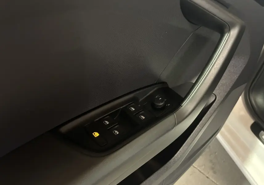 Gros plan sur la commande des vitres électriques et rétroviseurs sur la porte côté conducteur d'une Audi A1 blanche.