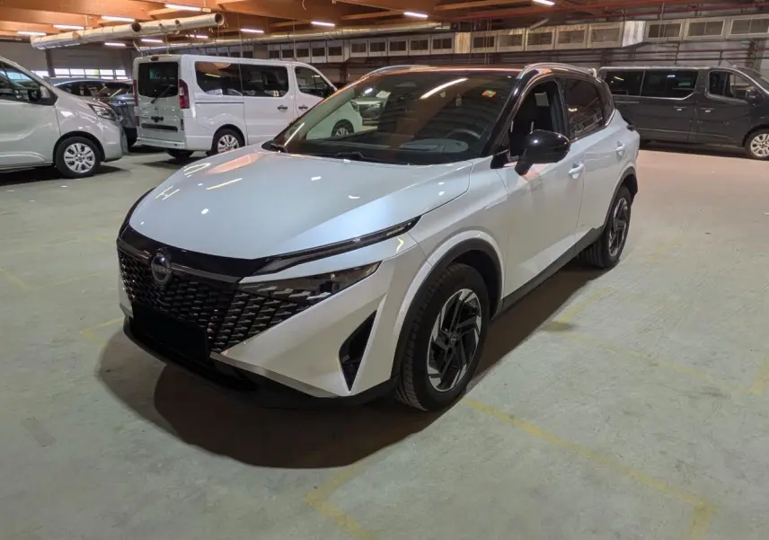 Nissan Qashqai blanc nacré avec toit noir, vu en 3/4 avant droit dans un parking intérieur.