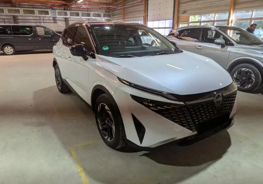 Nissan Qashqai blanc nacré avec toit noir, vu en 3/4 avant droit dans un garage intérieur.