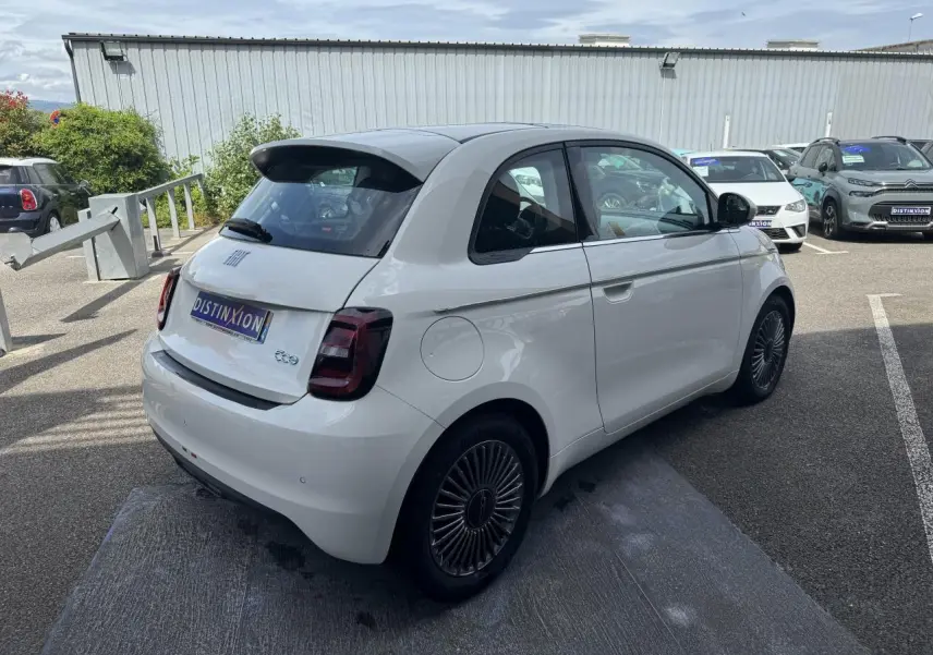 Vue 3/4 arrière droite d'une Fiat 500 électrique blanche avec jantes alliage 16'' et toit panoramique.