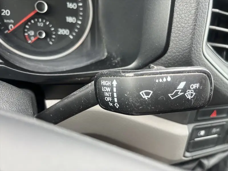 Gros plan sur la manette d'essuie-glace noire du Volkswagen Crafter Fourgon blanc, tableau de bord partiellement visible.