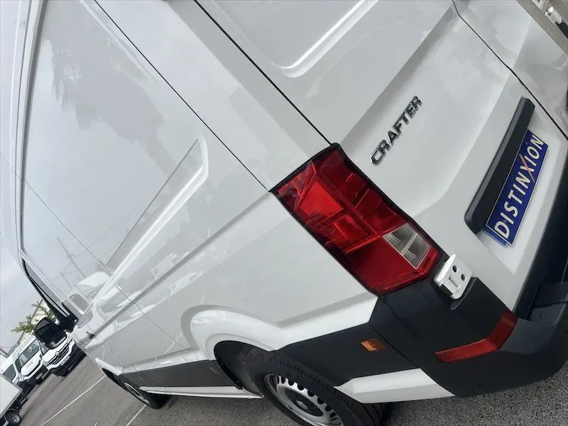 Vue arrière droite d'un utilitaire Volkswagen Crafter blanc, mettant en valeur son feu arrière et la porte latérale.