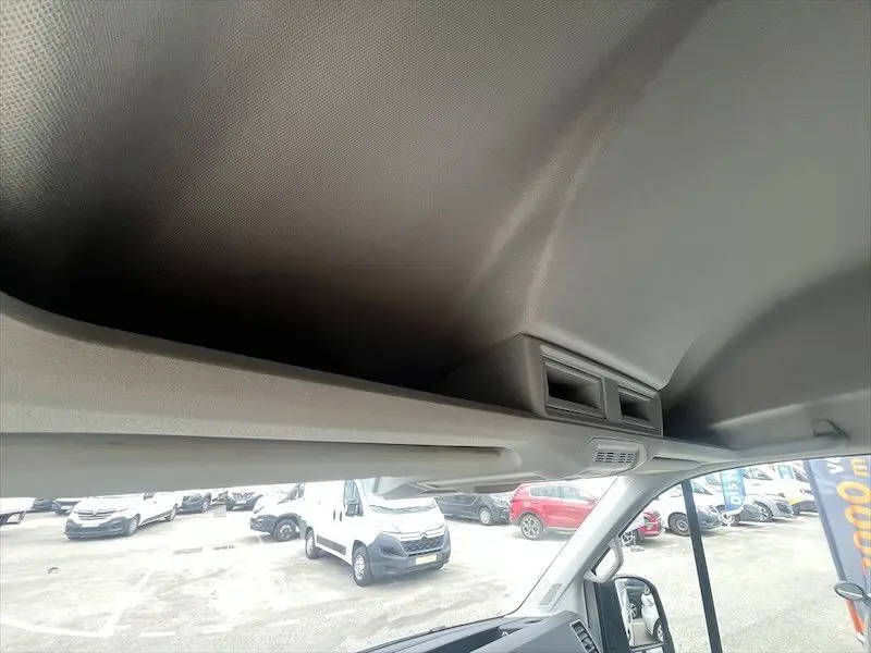 Vue intérieure du plafond et des aérateurs avant du Volkswagen Crafter fourgon blanc, avec aperçu du parking extérieur.