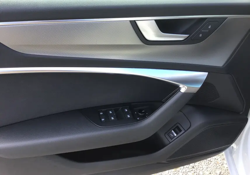 Vue rapprochée de la porte avant gauche de l’Audi A6 Avant blanc glacier, avec commandes électriques et insert aluminium.