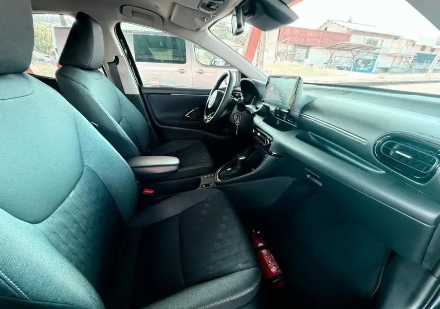 Intérieur avant droit de la Toyota Yaris Hybrid 116ch 2025, sièges noirs et tableau de bord moderne avec écran tactile.
