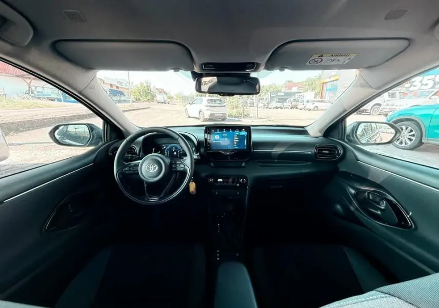 Intérieur noir de la Toyota Yaris Hybrid 2025 vu de face, avec tableau de bord moderne et écran tactile central.
