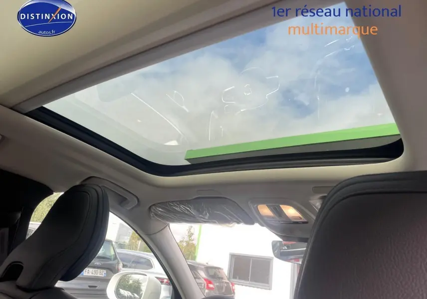 Toit panoramique en verre vu de l'intérieur avant du Volvo XC60 gris avec sièges en cuir noir.