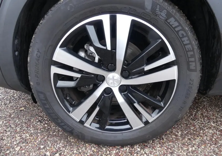 Gros plan sur la jante alliage 18 pouces bi-ton noir et argent du Peugeot 5008 GT noir métallisé.