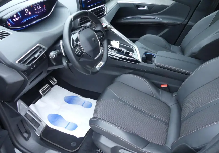 Intérieur avant droit du Peugeot 5008 GT 2023, sièges noirs, volant compact et tableau de bord numérique lumineux.