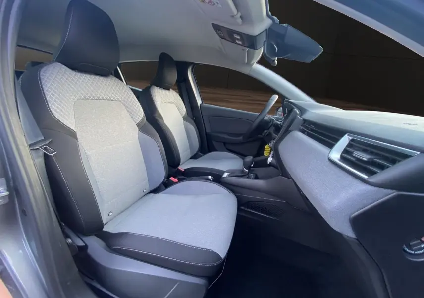 Vue intérieure côté gauche de la Renault Clio V E-Tech gris schiste, montrant les sièges avant en tissu gris à motif 3D.