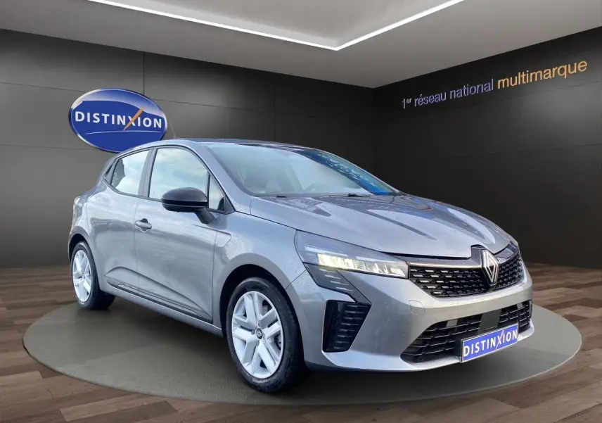 Renault Clio V E-Tech gris schiste vue 3/4 avant, avec projecteurs LED allumés et jantes alliage blanches.