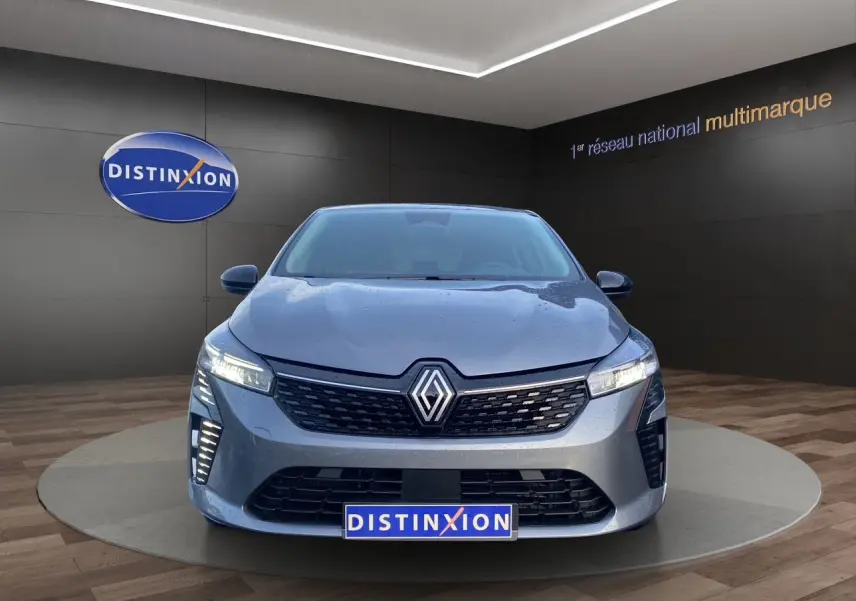 Vue avant d'une Renault Clio V E-Tech Full Hybrid gris schiste avec projecteurs LED allumés en showroom.