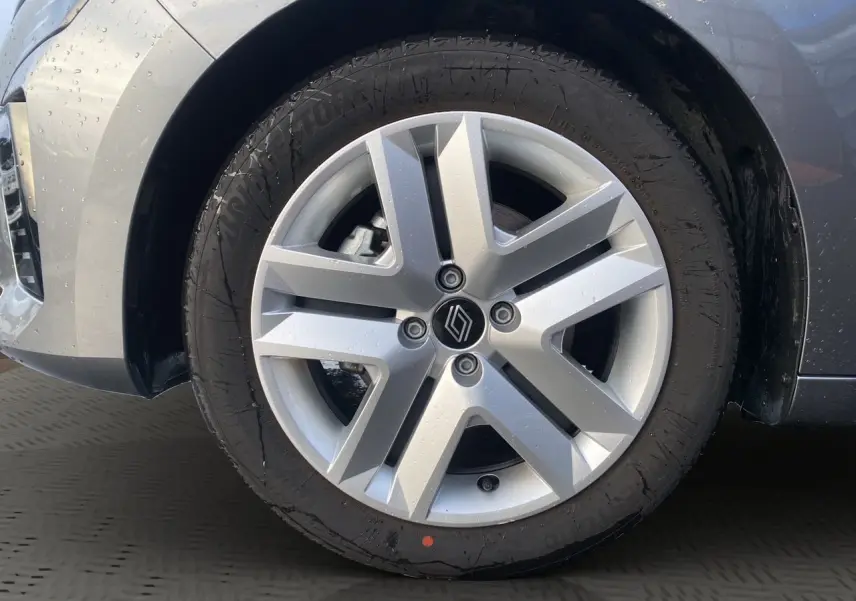 Gros plan sur la roue avant droite d’une Renault Clio V gris schiste, mettant en valeur la jante alliage moderne.