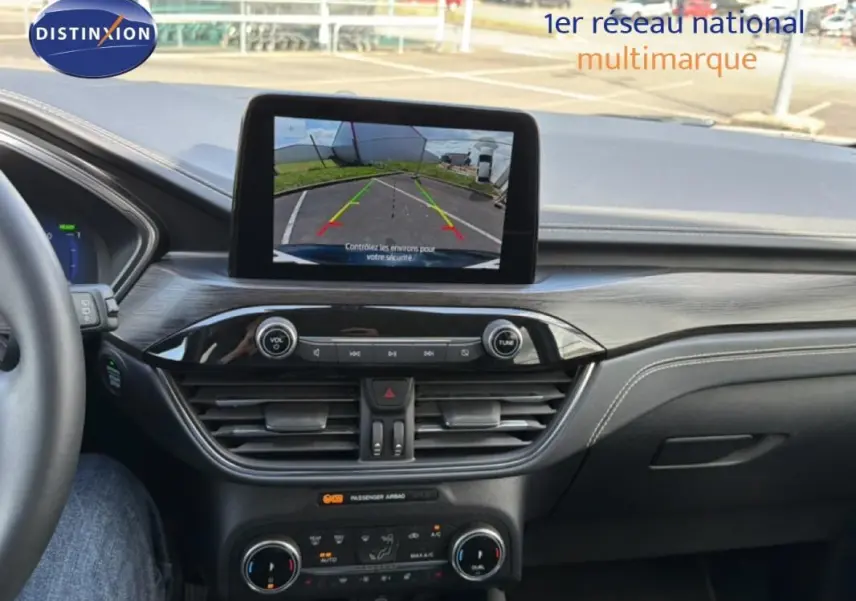 Vue intérieure du tableau de bord du Ford Kuga 2024 noir, avec écran tactile affichant la caméra de recul.