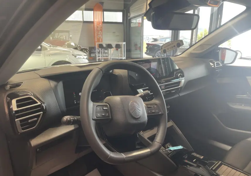 Vue intérieure côté conducteur de la Citroën C4 2026, volant cuir et tableau de bord numérique moderne.