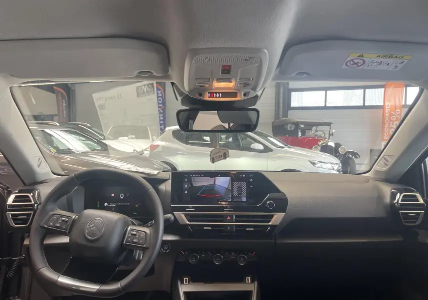 Vue intérieure avant du tableau de bord gris et noir de la Citroën C4 hybride avec écran tactile et volant multifonctions.