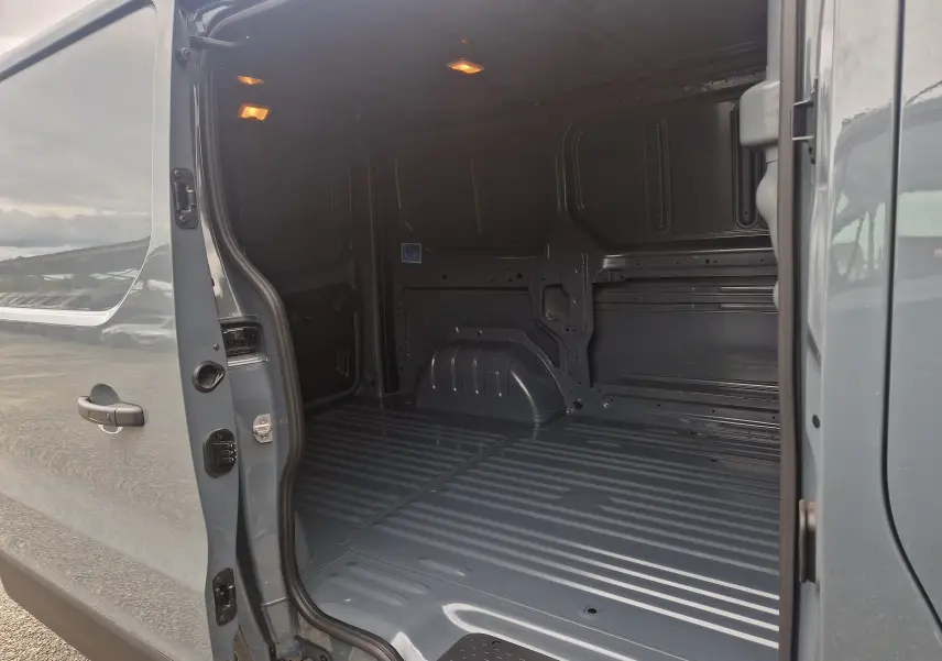 Vue intérieure du fourgon Renault Trafic L1H1 2025 gris urbain, montrant l'espace de chargement vide et éclairé.