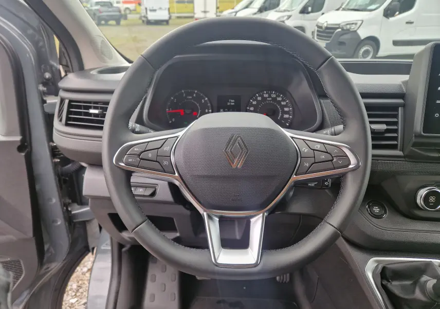 Vue centrée sur le volant noir du Renault Trafic Fourgon gris urbain 2025, avec commandes intégrées et tableau de bord visible.