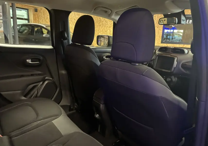 Vue intérieure arrière droite du Jeep Renegade noir, montrant les sièges en tissu noir et la console centrale.