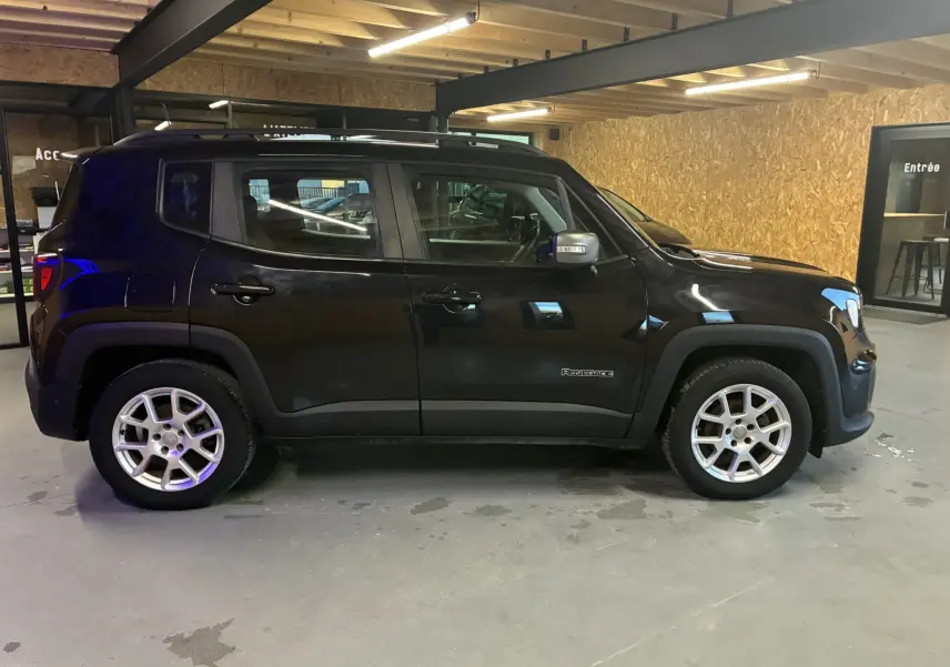 Profil côté gauche d'un Jeep Renegade noir 2019 avec jantes argentées, garé en intérieur sous plafond en bois.
