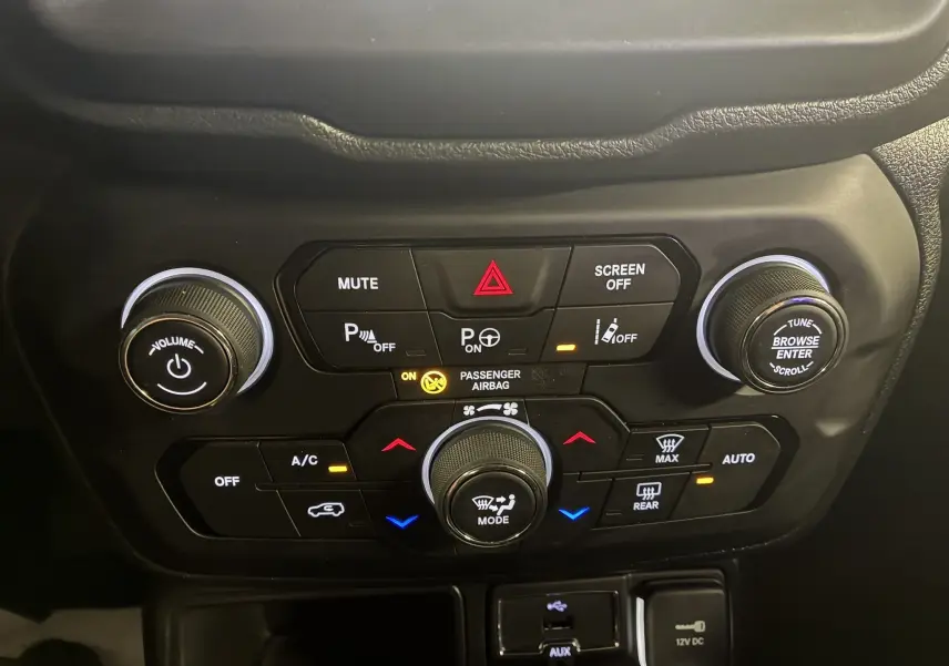Gros plan sur la console centrale du Jeep Renegade noir 2019, montrant les commandes climatisation et audio éclairées.