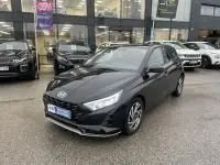 Vue 3/4 avant d’une Hyundai i20 2025 noir Phantom Metal avec phares LED et jantes alliage visibles sur parking extérieur.