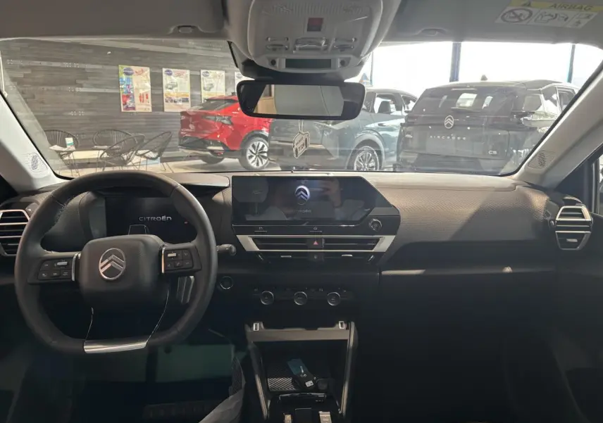 Vue intérieure avant du tableau de bord noir de la Citroën C4 hybride avec écran tactile central et volant multifonctions.