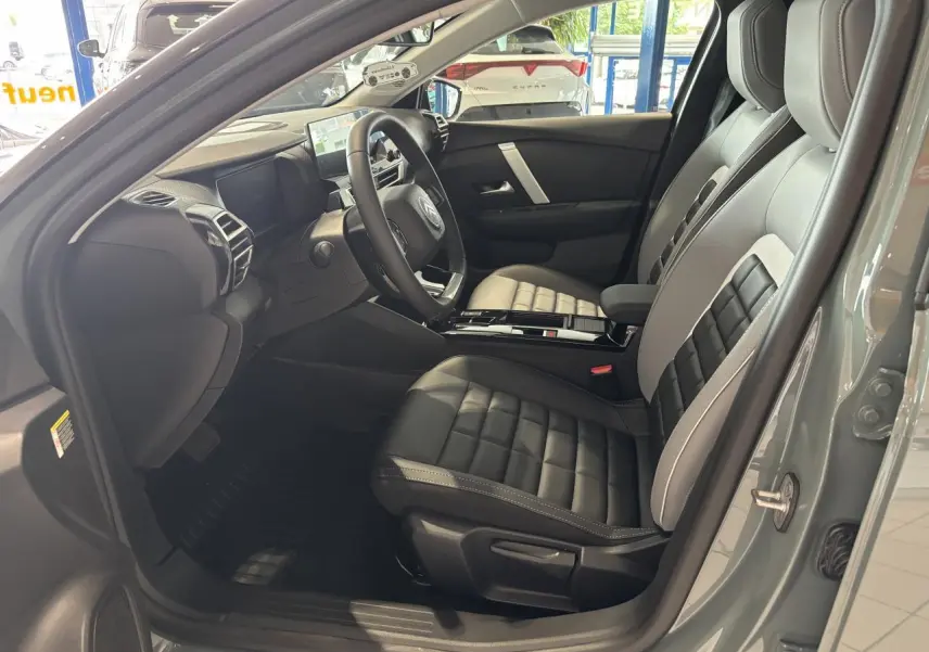 Vue intérieure côté conducteur de la Citroën C4 hybride 2026 en vert Manhattan, sièges Advanced Comfort noirs et gris.