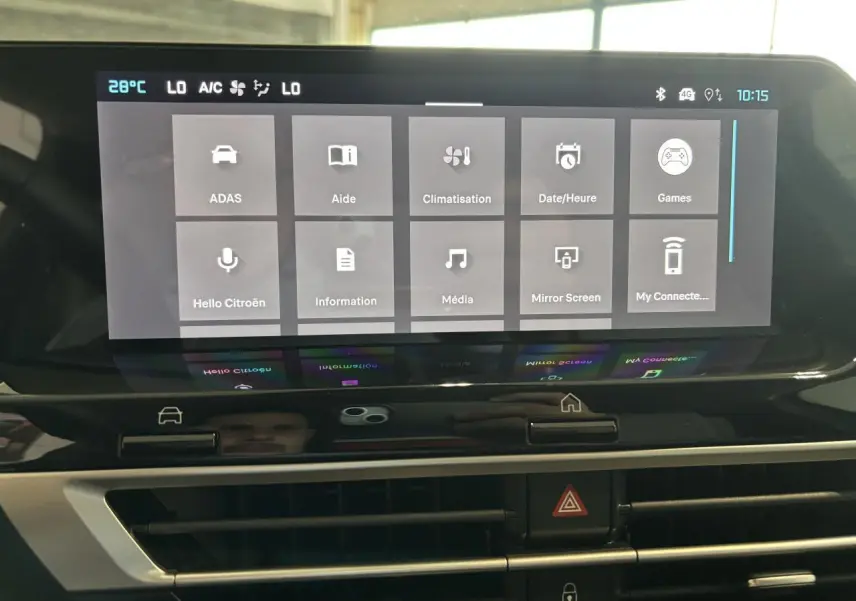 Écran tactile central de la Citroën C4 hybride 2026 montrant le menu principal avec commandes climatisation et aide.
