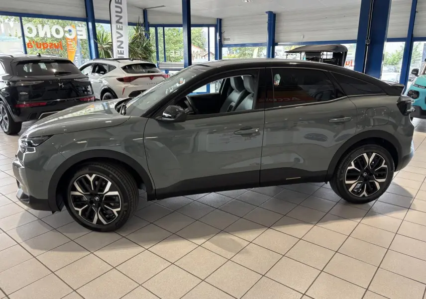 Profil côté gauche d'une Citroën C4 hybride 2026 gris Manhattan avec toit noir et jantes alliage 18 pouces.