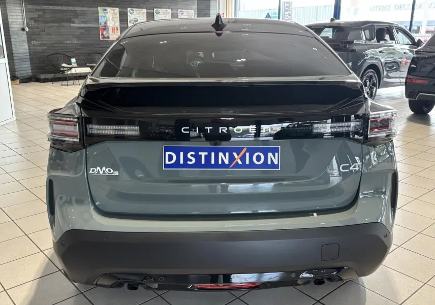 Vue arrière d'une Citroën C4 vert Manhattan avec toit noir Perla Nera en showroom, feux LED et logo distinctif.