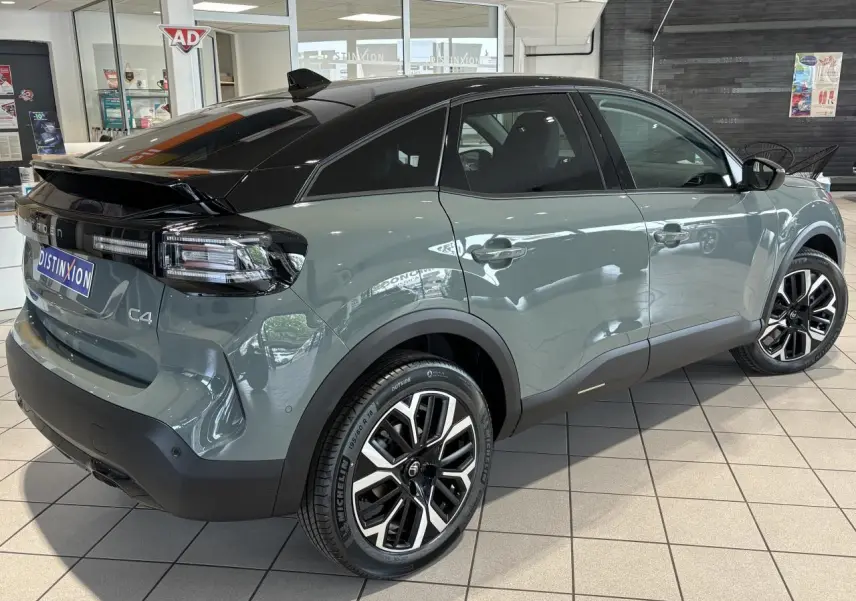 Vue 3/4 arrière droite d'une Citroën C4 2026 vert Manhattan avec toit noir Perla Nera et jantes alliage 18 pouces.