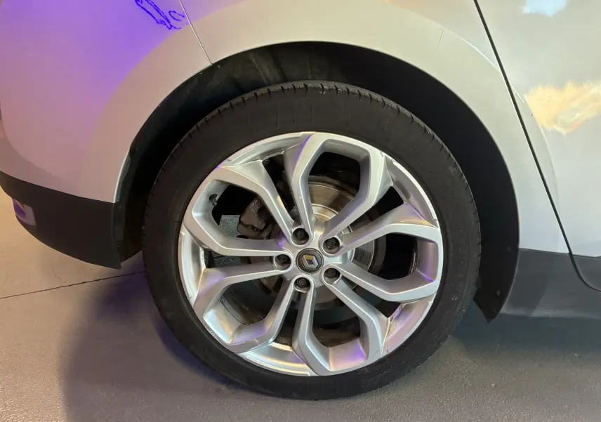 Gros plan sur la roue avant gauche gris métallisé d'un Renault Grand Scenic 2017 avec jante alliage à motifs modernes.