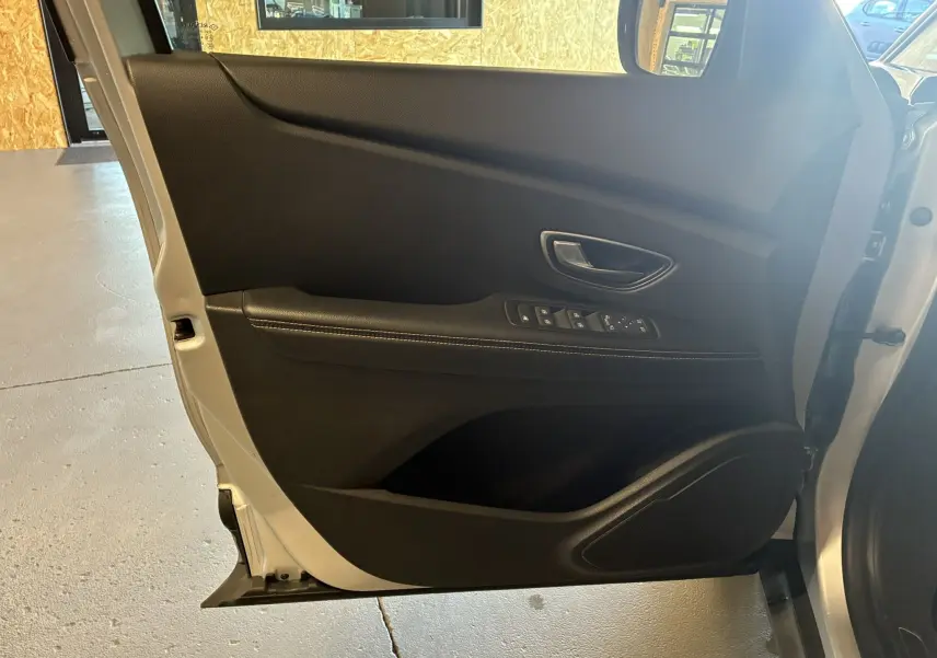 Vue rapprochée de la porte avant gauche gris clair du Renault Grand Scenic 2017 avec commandes de vitres et poignée intégrée.