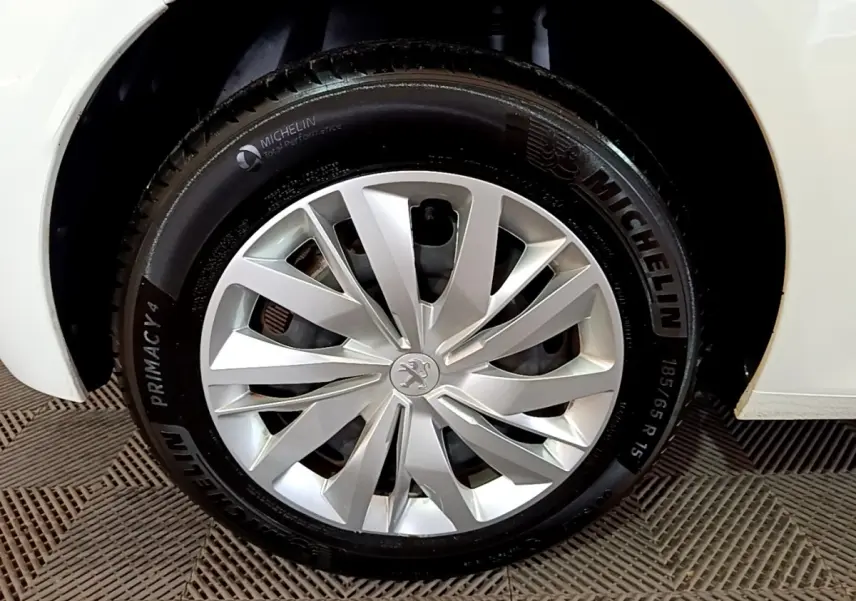 Gros plan sur la roue avant droite d'une Peugeot 208 blanche avec jante alliage et pneu Michelin.