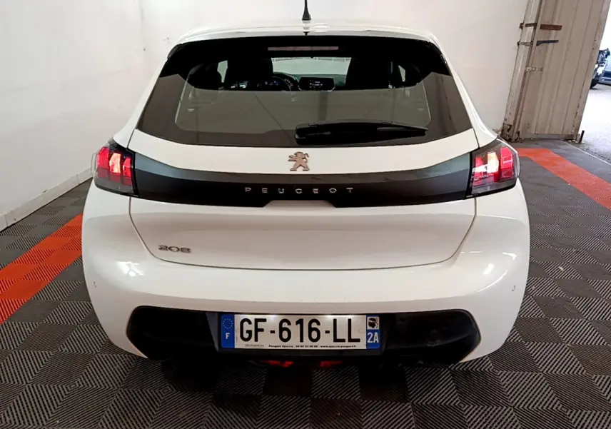 Vue arrière d'une Peugeot 208 blanche de 2022 avec feux arrière allumés dans un garage.