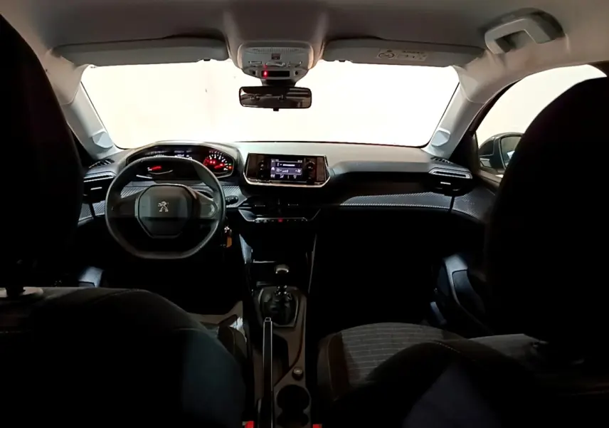 Vue intérieure avant de la Peugeot 208 blanche, tableau de bord moderne avec écran tactile et volant compact.