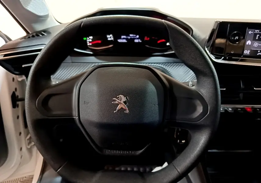 Vue rapprochée du volant noir de la Peugeot 208 1.5 BlueHDi 2022 avec tableau de bord et écran tactile visibles.