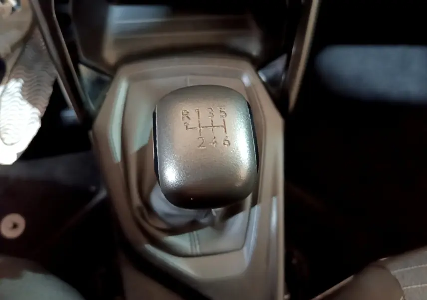 Gros plan sur le levier de vitesses manuel de la Peugeot 208 blanche, montrant les six rapports et la marche arrière.