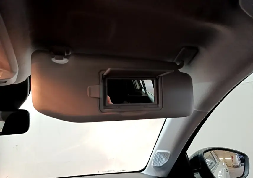 Intérieur de la Peugeot 208 blanc, vue côté passager avec pare-soleil rabattable et miroir de courtoisie ouvert.