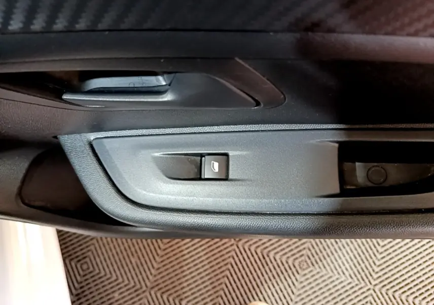 Détail de la commande de lève-vitre côté conducteur dans l'intérieur noir d'une Peugeot 208 blanche 2022.