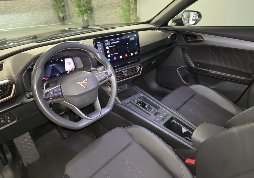 Intérieur de la CUPRA Formentor 1.4 e-Hybrid 2023 vu côté conducteur, tableau de bord noir avec écran tactile et volant sport cuir.