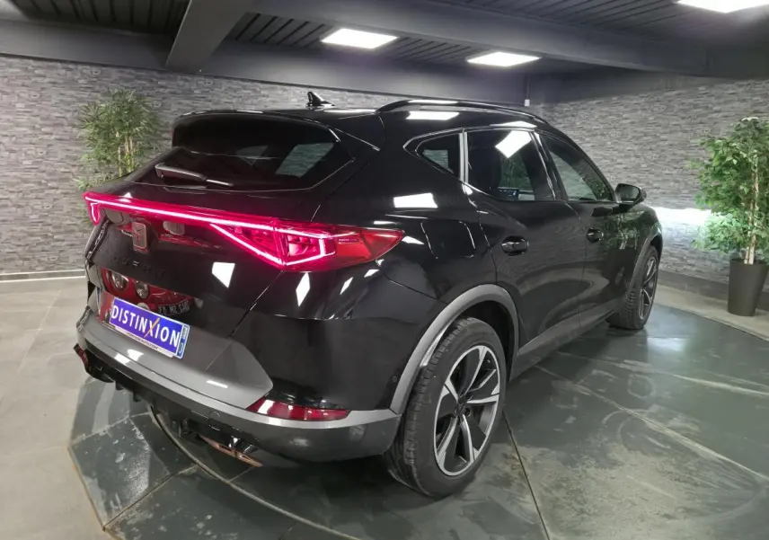 Vue 3/4 arrière droite du CUPRA Formentor noir avec bandeau LED arrière et jantes alliage 18 pouces en intérieur showroom.