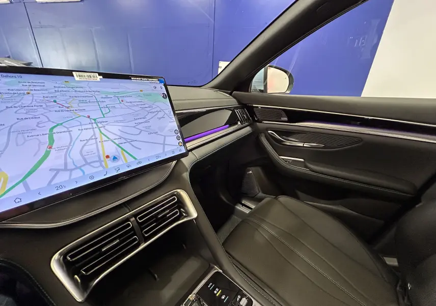 Vue intérieure côté passager du BYD SEAL U 2025, avec écran tactile GPS, éclairage d'ambiance violet et sellerie cuir noir.