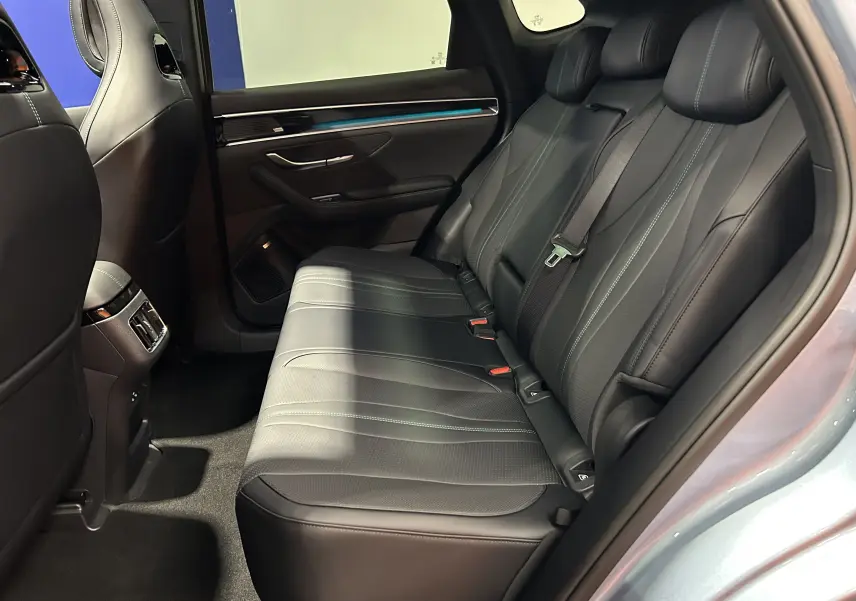 Vue intérieure côté droit sur la banquette arrière en cuir noir du BYD SEAL U 2025 avec finitions soignées et éclairage d'ambiance bleu.