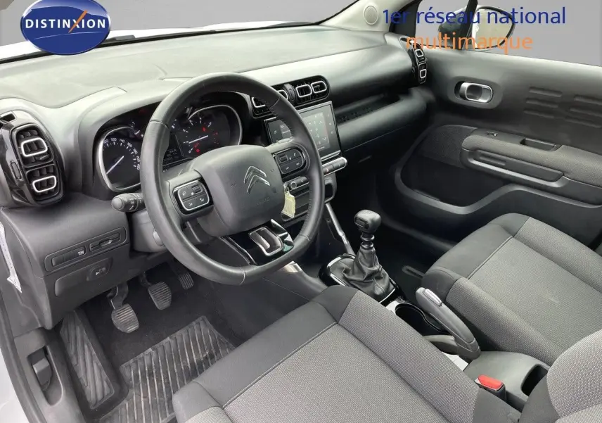 Intérieur du Citroën C3 Aircross 2023 en tissu gris, vue côté conducteur avec volant multifonction et boîte manuelle.