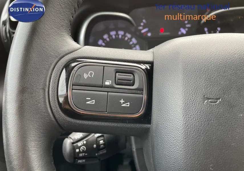 Gros plan sur les commandes du volant du Citroën C3 Aircross 2023 en blanc polaire, mettant en valeur les boutons multifonctions.