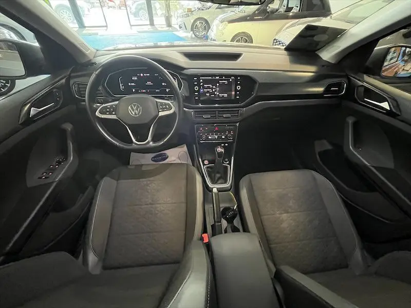Intérieur du Volkswagen T-Cross 1.0 TSI 110 DSG Carat 2021, vue frontale sur tableau de bord et sièges gris foncé.
