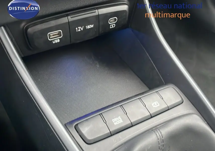 Gros plan sur la console centrale noire de la Hyundai i20 2025, montrant les ports USB, prise 12V et boutons de commande.